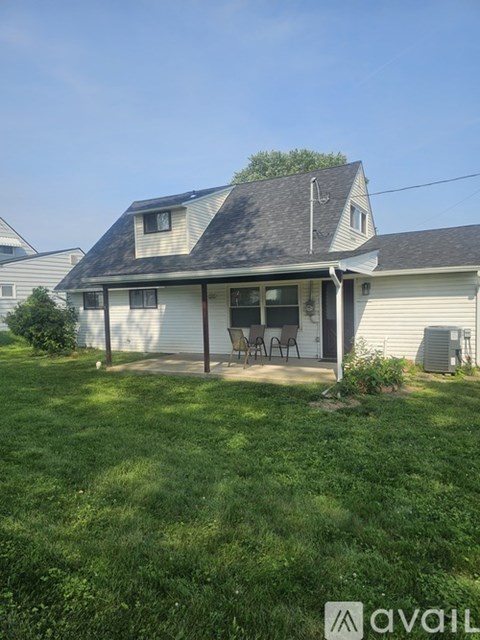 A house with a covered patio and a lawn in front.
