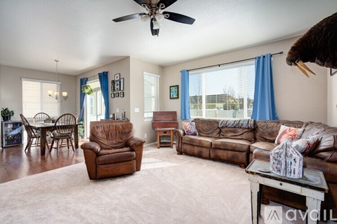 A living room with a brown leather couch and a ceiling fan.