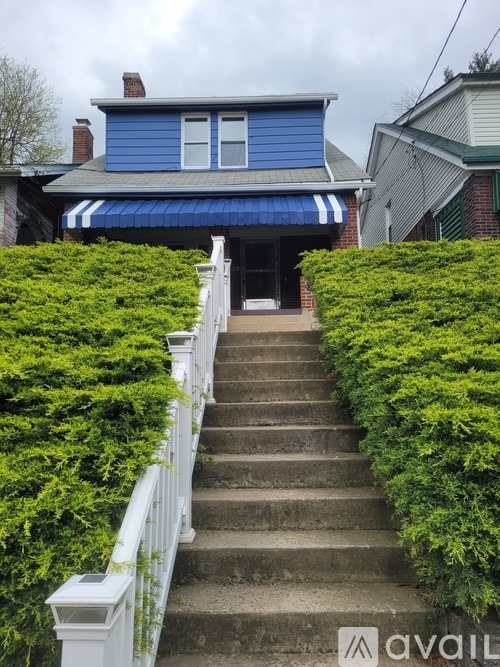 A concrete patio with a white fence and a staircase leading to a green area.