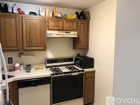 A kitchen with wooden cabinets and a black dishwasher.