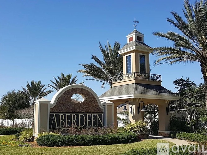 A small building with a tower and a sign that says Aberdeen in front of some trees.