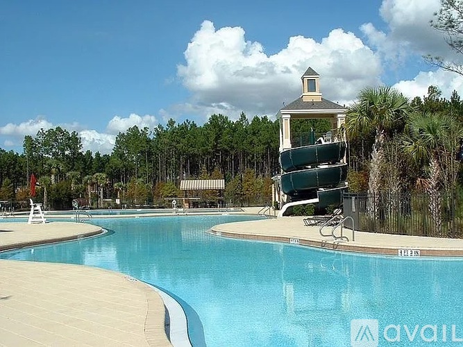 A pool with a water slide and a lifeguard tower.