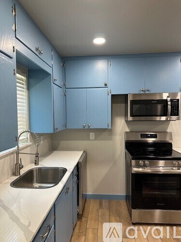 A kitchen with blue cabinets and stainless steel appliances.