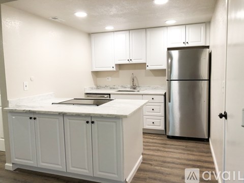 A kitchen with white cabinets and a stainless steel refrigerator.