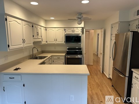 A kitchen with white cabinets and appliances.
