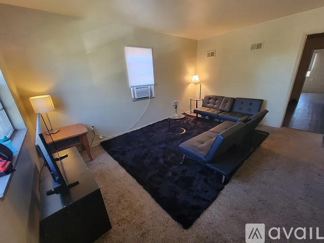 A black sofa with a white table in front of it in a room.