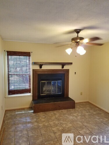 A living room with a fireplace and a ceiling fan.