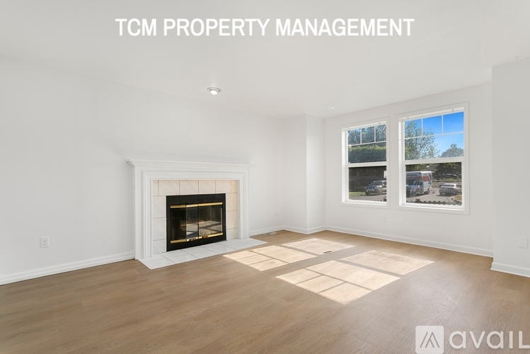 A spacious living room with a fireplace and a large window.