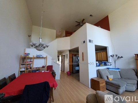 A living room with a red table and a grey couch.