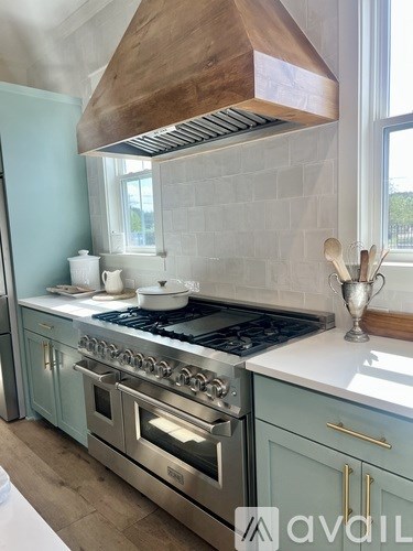 A kitchen with a stove top oven and a hood above it.