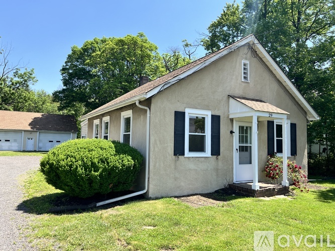 A small house with a white door and black shutters is for sale.