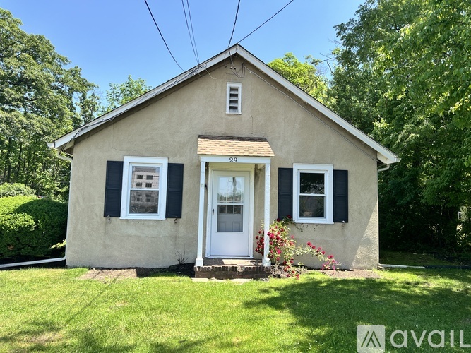 A small house with a white door and black shutters is for sale.
