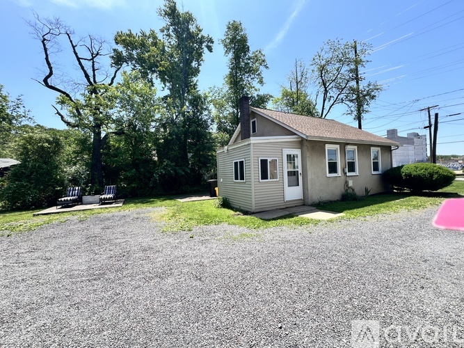 A small house with a gravel driveway in front.