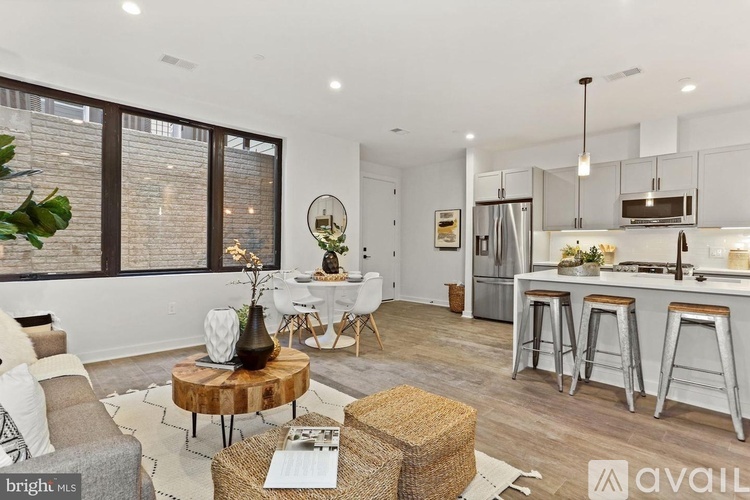 A modern kitchen and living room with a dining table and bar stools.