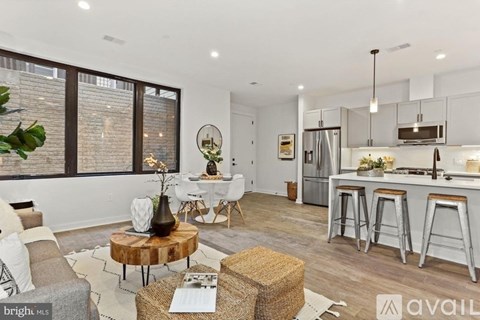A modern kitchen and living room with a dining table and bar stools.
