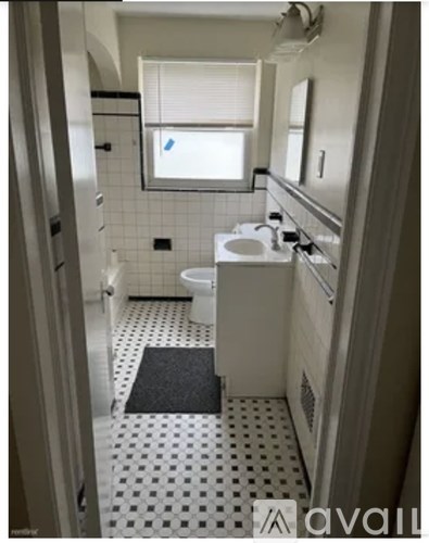 A bathroom with a toilet, sink, and a window.