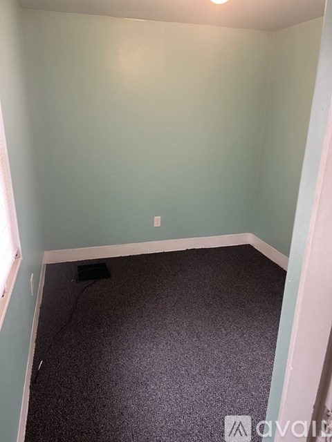 A room with a carpeted floor and a window on the left side.