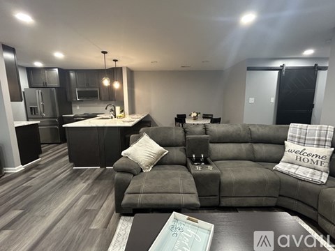 A modern kitchen and living room with a grey sofa and wooden floors.