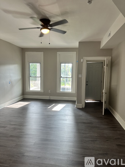 A room with a ceiling fan and wooden flooring.
