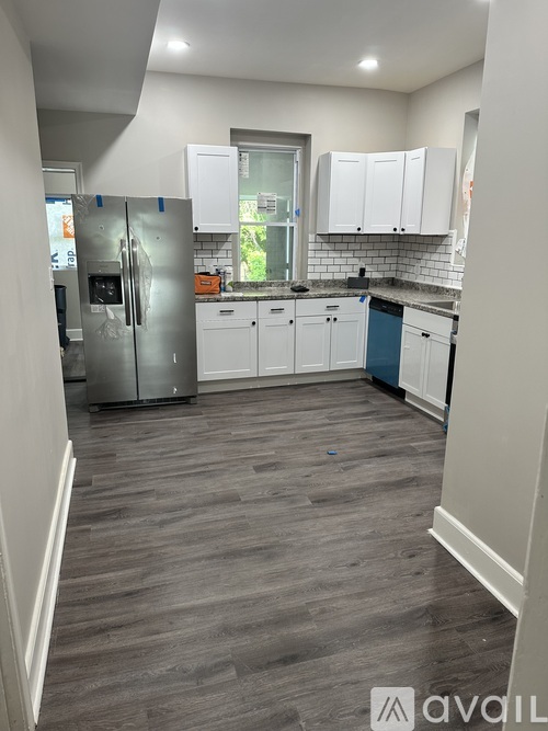 A kitchen with white cabinets and a grey floor.