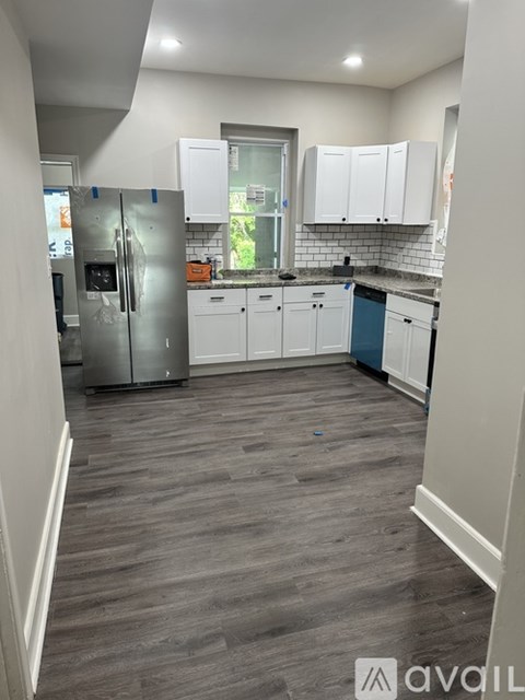A kitchen with white cabinets and a grey floor.