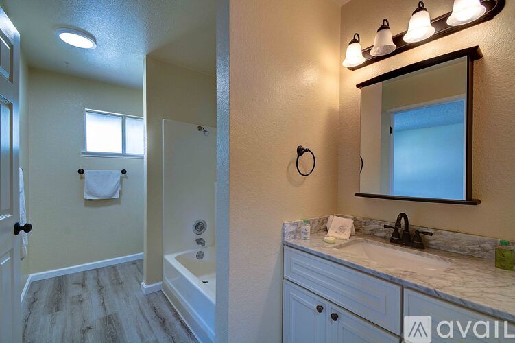 A bathroom with a tub, sink, and mirror.