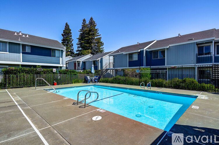 A pool surrounded by a fence and a few houses.
