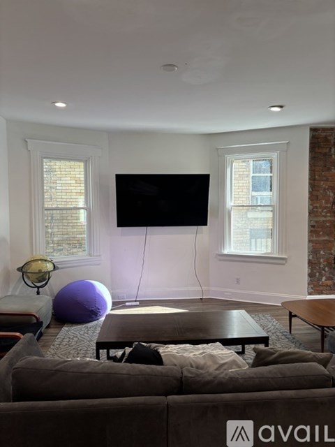 A living room with a grey couch and a flat screen TV mounted on the wall.
