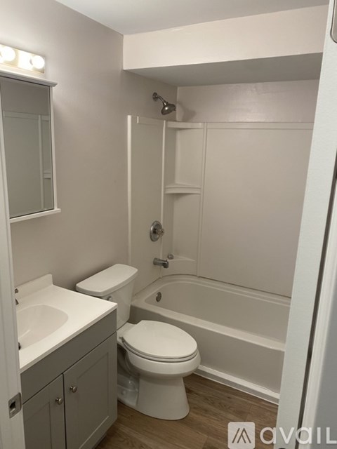 A white toilet sits in a small bathroom with a sink and a shower.