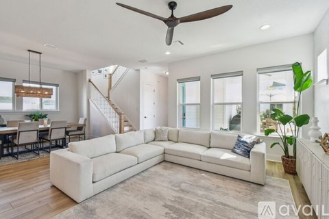 A spacious living room with a white sofa and a staircase in the background.