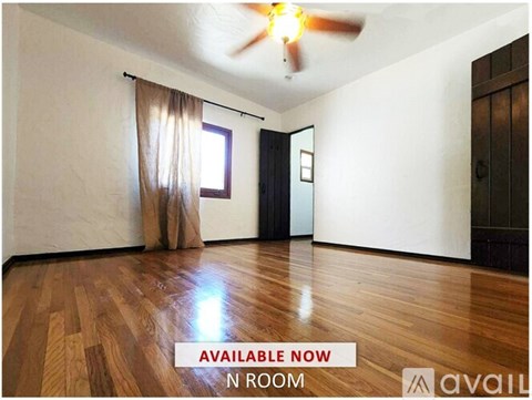 A room with wooden flooring and curtains on the windows.