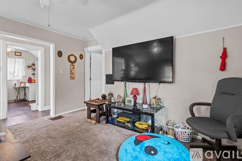 A living room with a television, a chair, and a table with various objects on it.