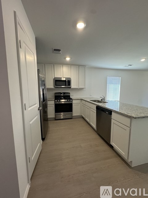 A kitchen with white cabinets and a wooden floor.