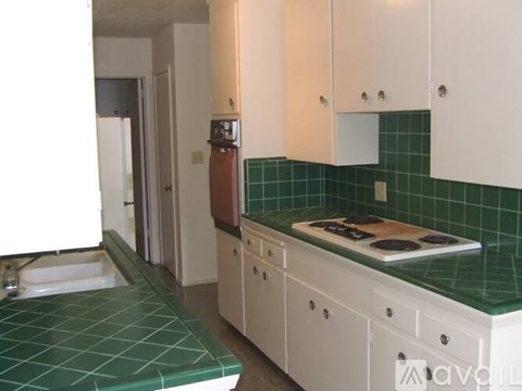 A kitchen with white cabinets and a green tiled backsplash.