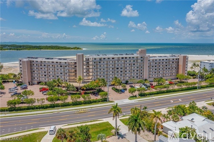 A large hotel complex with a beachfront view and a parking lot in front.