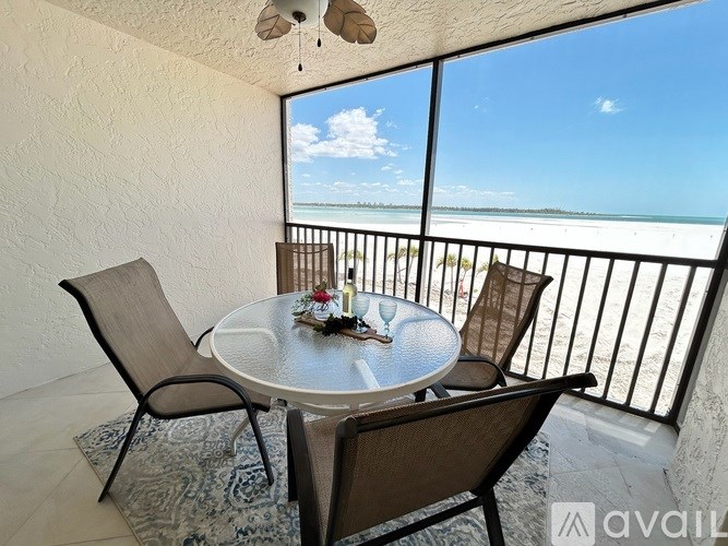 A balcony with a table and chairs overlooking the beach.