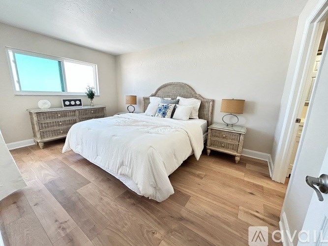 A bedroom with a large bed and a wooden floor.