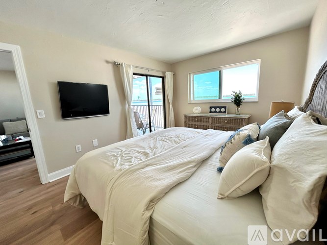A bedroom with a large bed and a flat screen TV mounted on the wall.
