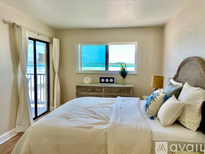 A bedroom with a large bed and a window overlooking the water.