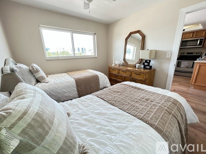 A bedroom with two beds and a dresser with a mirror.