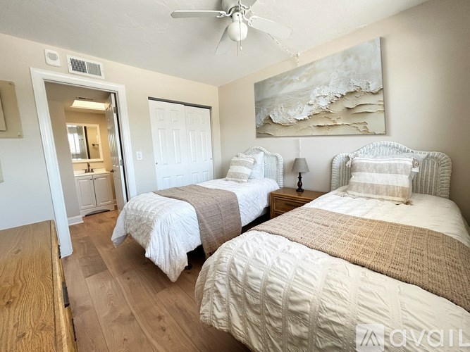 Two twin beds in a room with wooden floors and white walls.