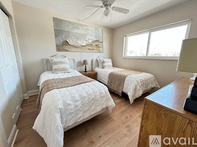 A bedroom with two beds and a ceiling fan.