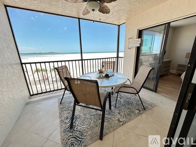 A balcony with a table and chairs overlooking the beach.