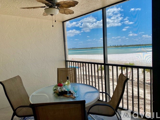 A balcony with a table and chairs overlooking a beach.