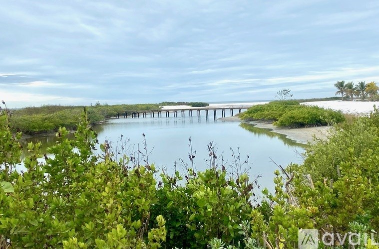 A serene landscape with a body of water, a bridge, and lush greenery.
