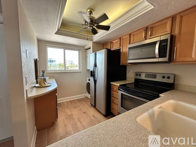 A kitchen with a refrigerator, microwave, oven, and sink.