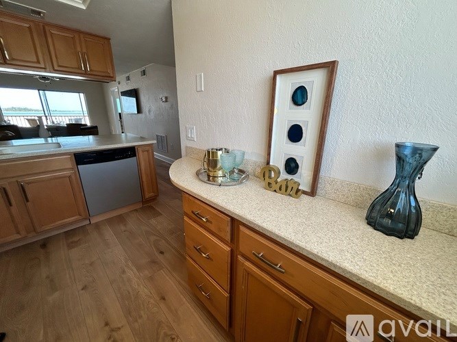 A kitchen with wooden cabinets and a countertop with a vase and a picture frame.