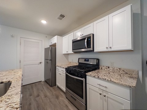 A kitchen with a white countertop and a bar stool.