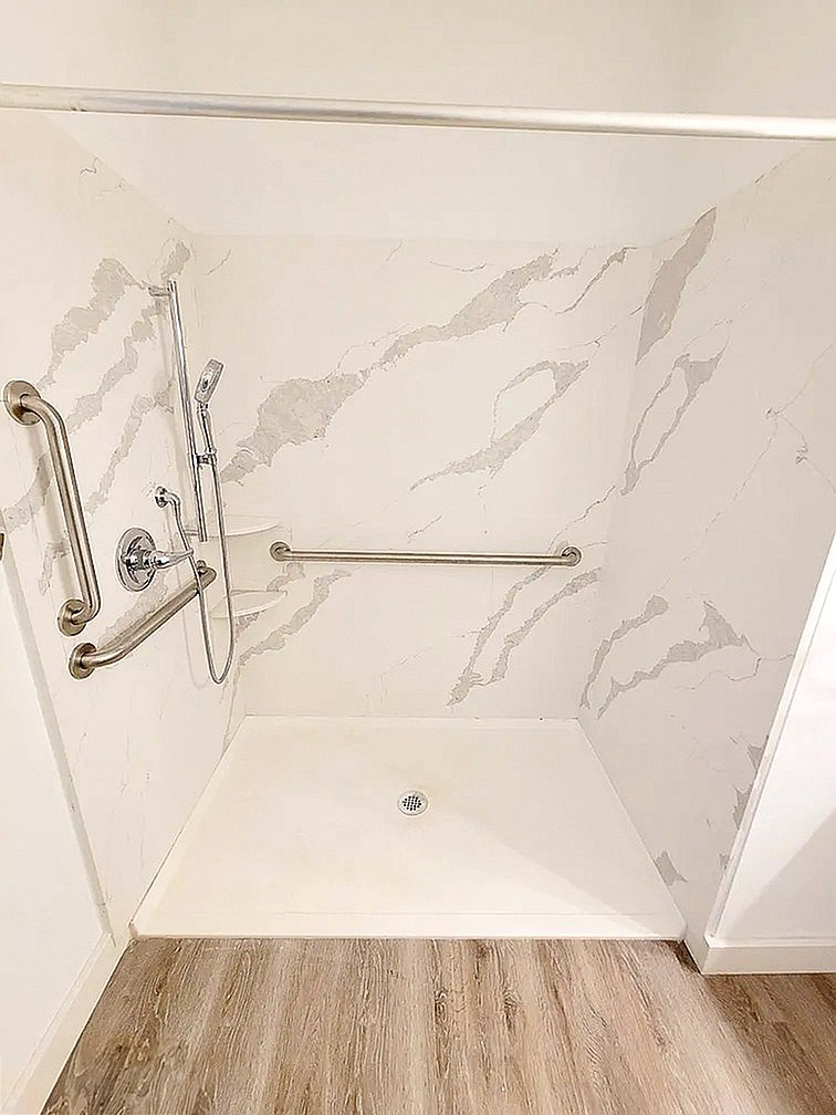 A white bathroom with a marble patterned shower.