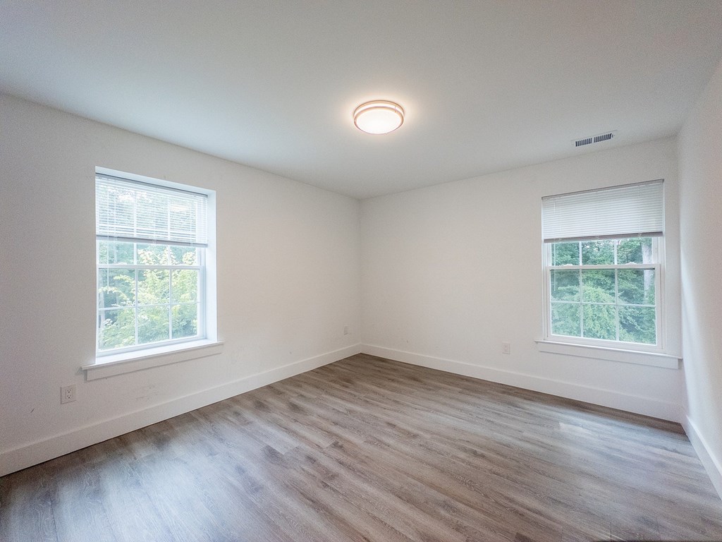 A room with a window and a wooden floor.